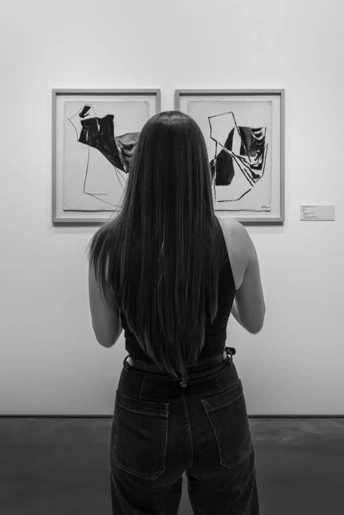 Visiteuse observant des œuvres dans un musée, métaphore du positionnement et du choix
